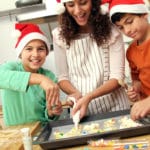 woman bakes holiday cookies with two boys