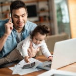 Man working from home with his child on his lap