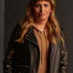 A dark blonde long haired woman wearing a dark brown leather jacket posing for a picture.